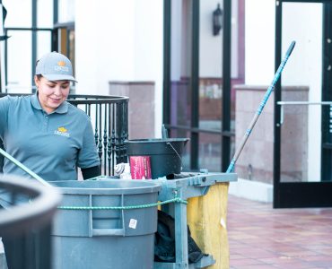 Person putting trash into trash can demonstrating janitorial services from Crown Facility Solutions