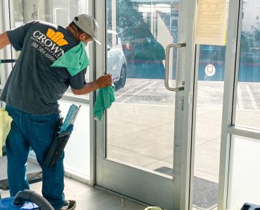 Crown Facility Solutions worker cleaning glass door for construction cleanup