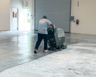 Person using machine to deep clean commercial warehouse building