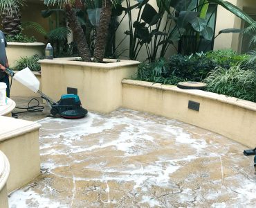 Crown Facility Solutions Worker deep cleaning concrete floor in a common area