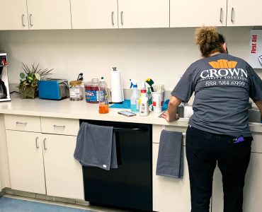 Worker providing janitorial cleaning services in commercial kitchen