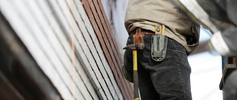 Close-up of a Crown Facility Solutions team member with a hammer and tool belt, working on a construction or maintenance project.