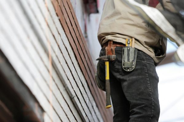 Close-up of a Crown Facility Solutions team member with a hammer and tool belt, working on a construction or maintenance project.